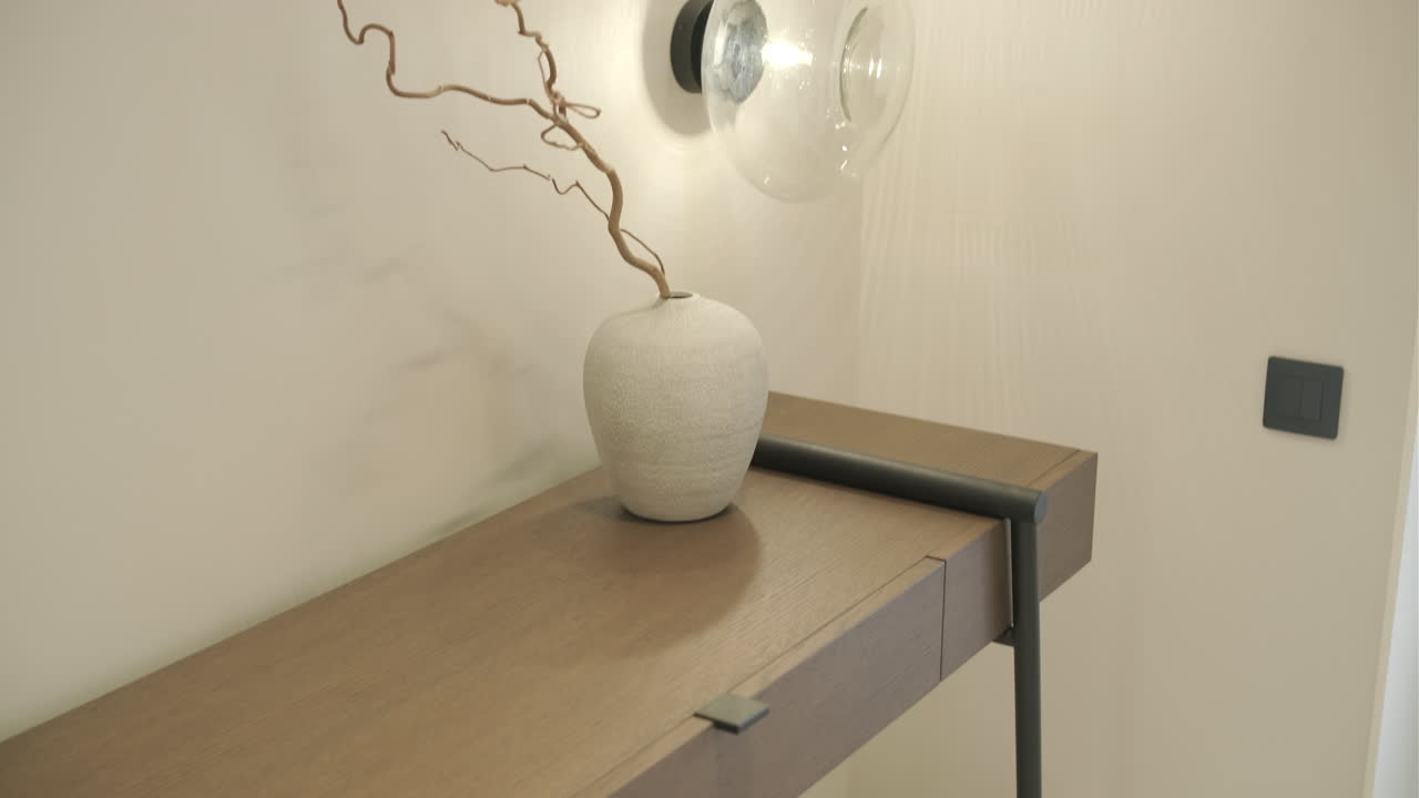 Mesa consola moderna con jarrón decorativo y lámpara de pared en interior de hogar