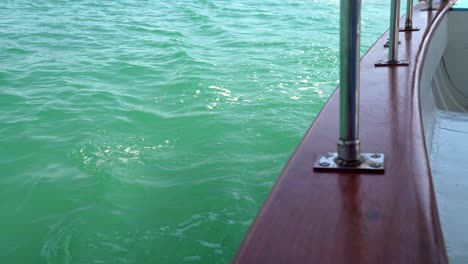Green-ocean-water-ripples-against-the-of-hull-of-a-wooden-boat