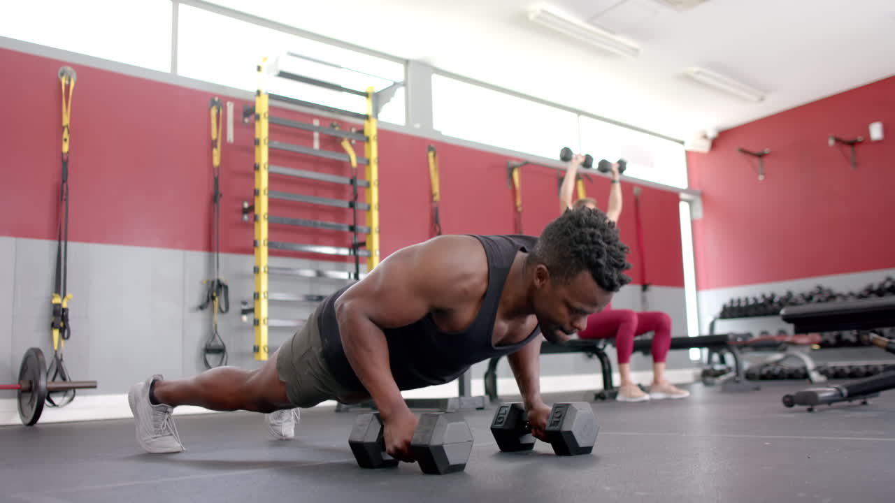 hombre afroamericano en forma haciendo flexiones en el gimnasio