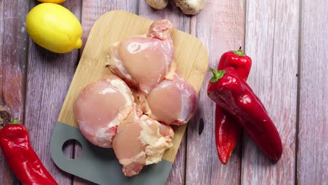 raw chicken thighs with red peppers and lemons on a cutting board