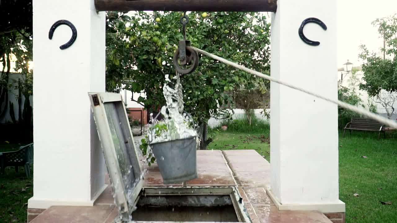 양동이에서 물이 튀면서 수동 도르래의 도움으로 우물에서 끌어낸 물의 슬로우 모션 샷