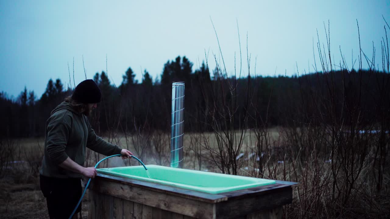 에서 물로 목재로 불타는 핫을 채우는 남자