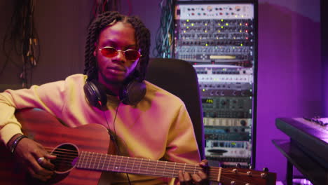 Hombre-Afroamericano-Tocando-La-Guitarra-Y-Posando-Para-La-Cámara-En-El-Estudio-De-Grabación