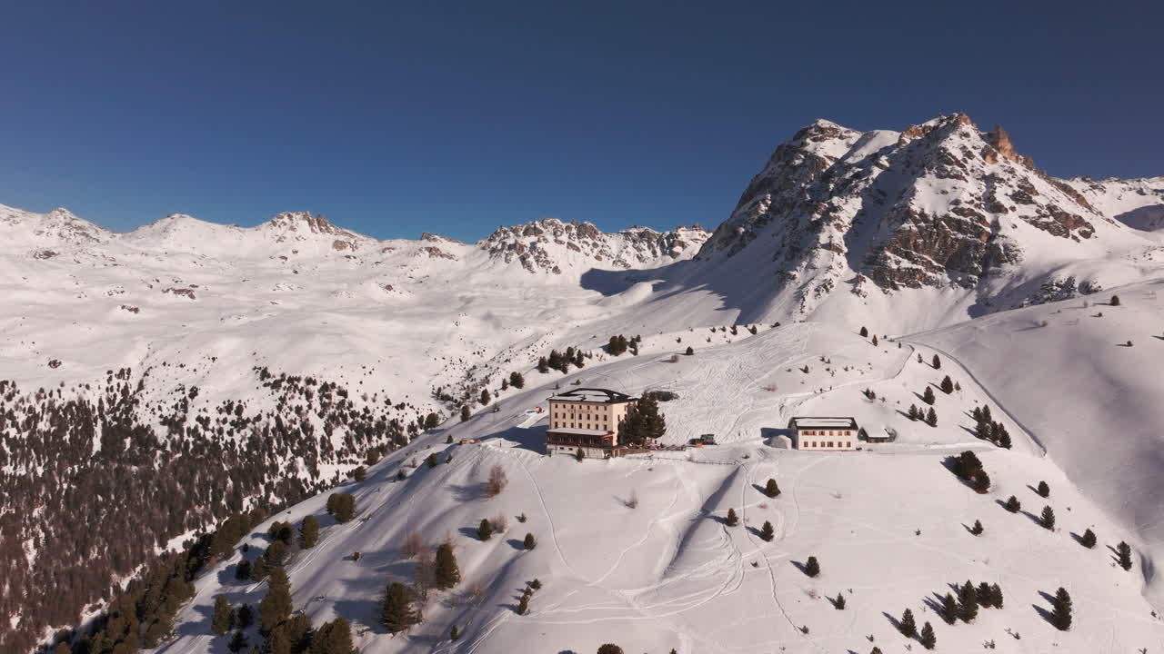 Drone aerial of Hotel Weisshorn, Switzerland. Iconic alpine hotel surrounded by snowy peaks and forests, offering breathtaking mountain scenery for travel, tourism and cinematic stock footage