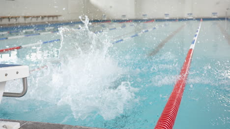 Splashing into swimming pool, swimmer making big splash during swim practice