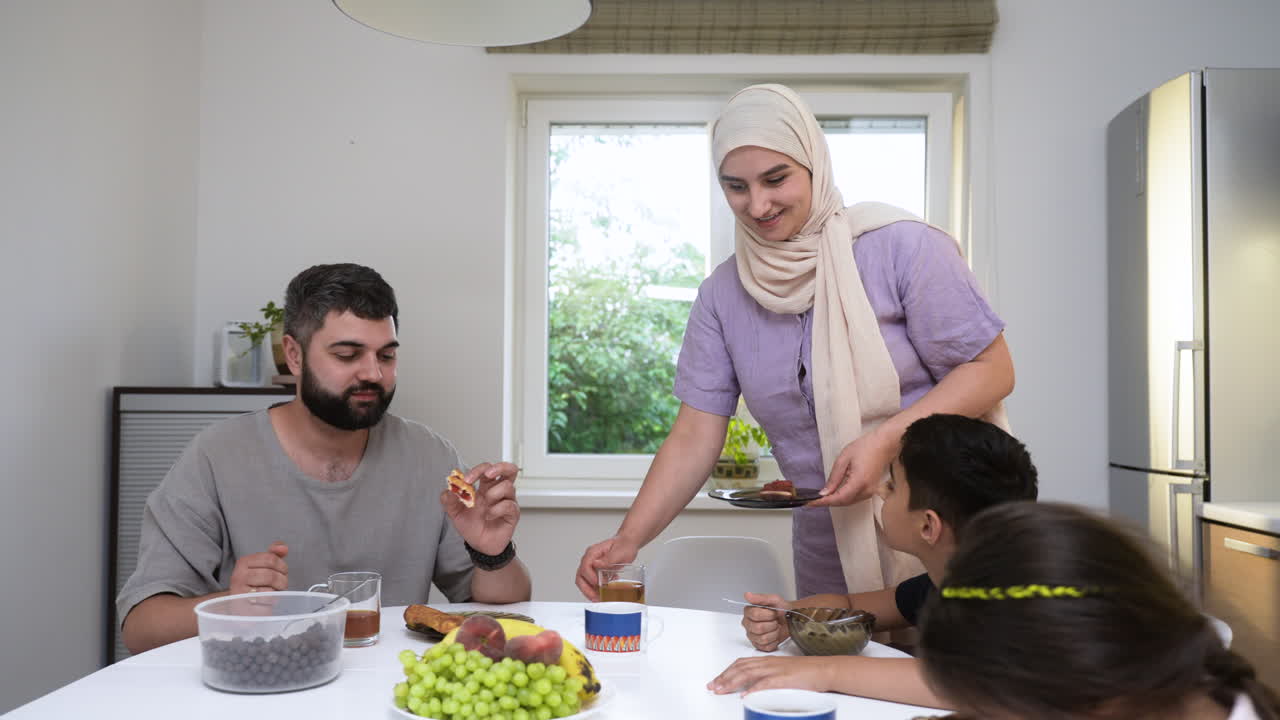 una mujer islámica con hijab preparando el desayuno en la cocina.