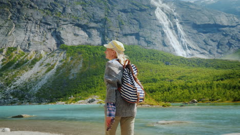 el viajero camina entre los majestuosos acantilados con cascadas y glaciares en la cima viajando en noruega