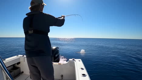 man fishing on a boat in the open ocean