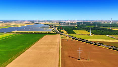 wind turbine energy landscape. aerial view of a vibrant agricultural landscape featuring wind turbines and solar panels under a clear blue sky