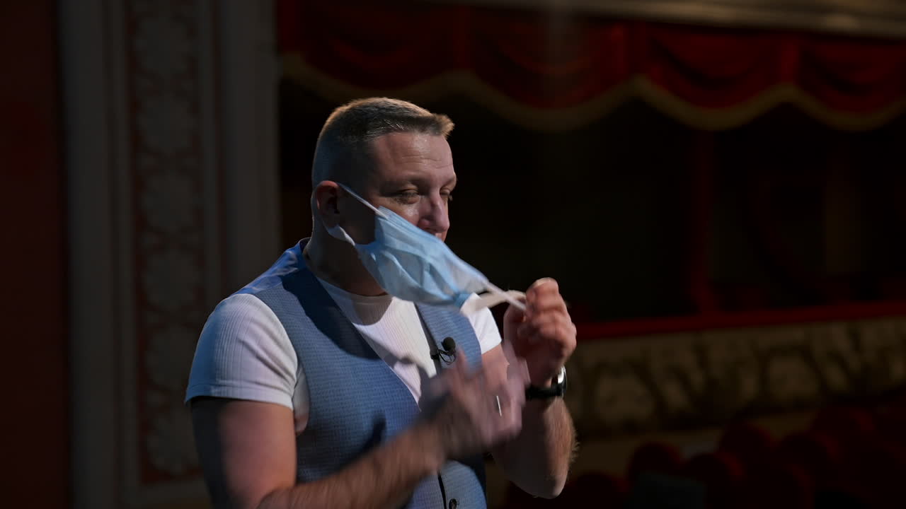 Man performs on stage during pandemic. Man in medical masks on stage in theater during pandemic