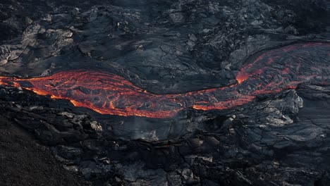 río de lava fluye sobre la superficie de la tierra rodeado de roca basáltica oscura
