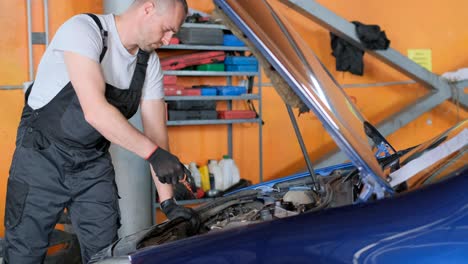 auto mechanic checking car oil level in a garage
