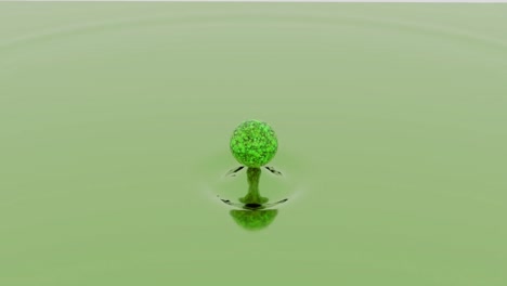 esfera verde cayendo en una superficie líquida