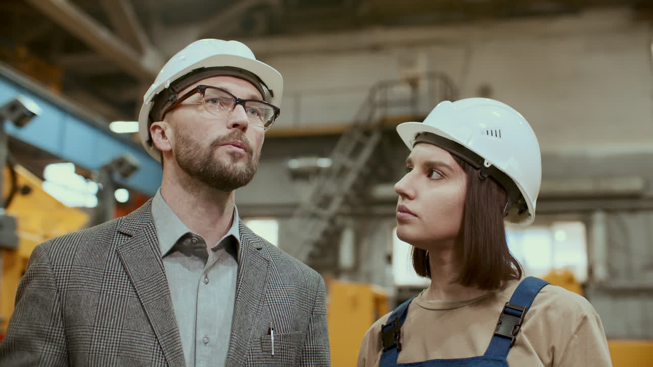 мужчина-инженер и женщина-работник завода обсуждают промышленное оборудование