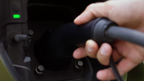 extreme closeup of driver recharging ev car, connecting plug