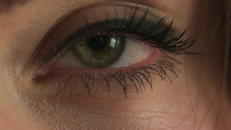 primer plano del ojo verde de una joven caucásica cerrando y abriendo
