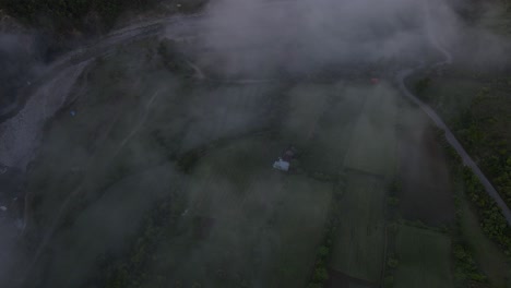 vista aérea desde un avión no tripulado, mirando hacia abajo al valle cubierto de niebla con baños termales de benja y el río vjosa en albania