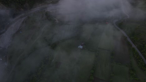 aerial view from a drone, looking down at the fog-covered valley with benja thermal baths and the vjosa river in albania