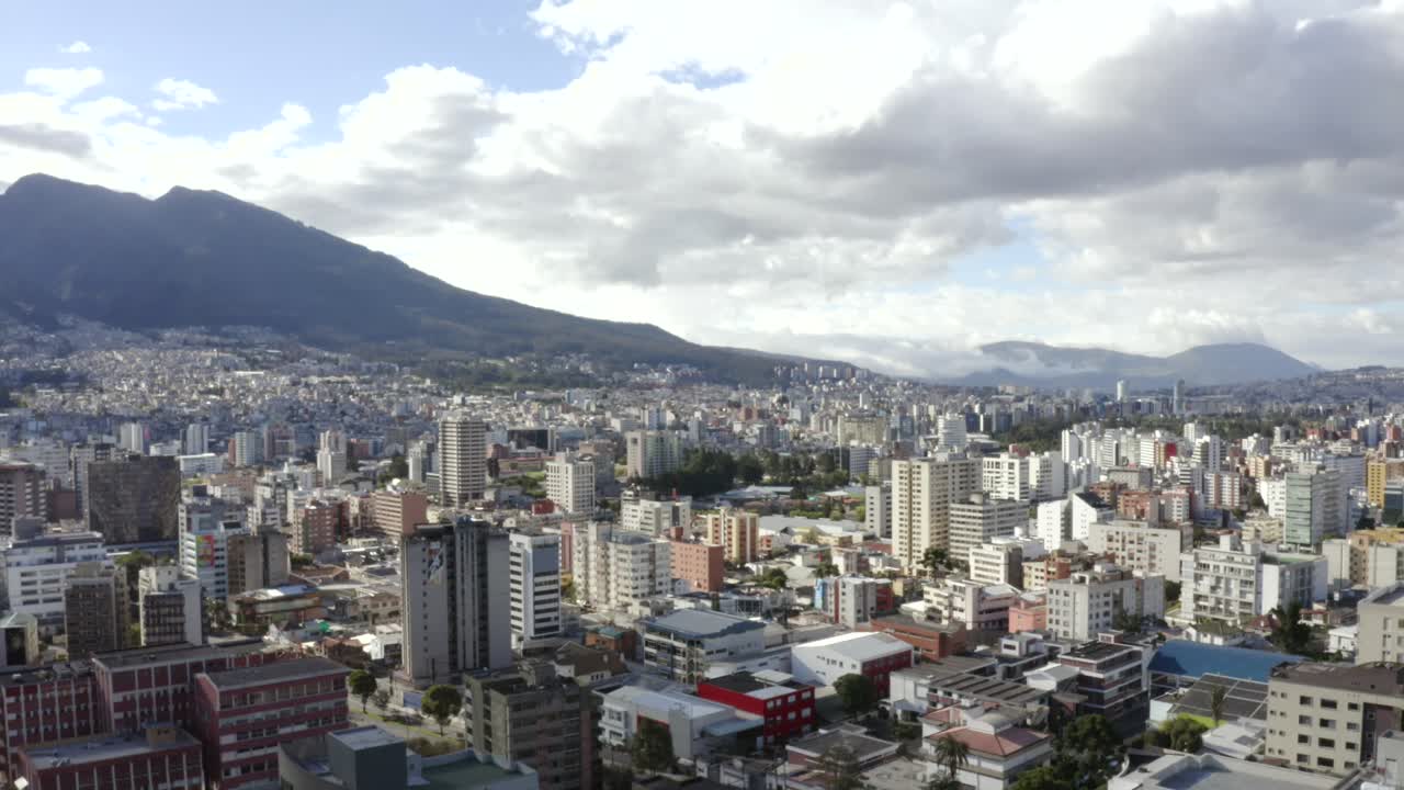 Ripresa aerea con drone della parte nord della città di Quito, Ecuador. Si vedono edifici e, sullo sfondo, il monte Pichincha con le sue antenne. Anche alberi e case della città