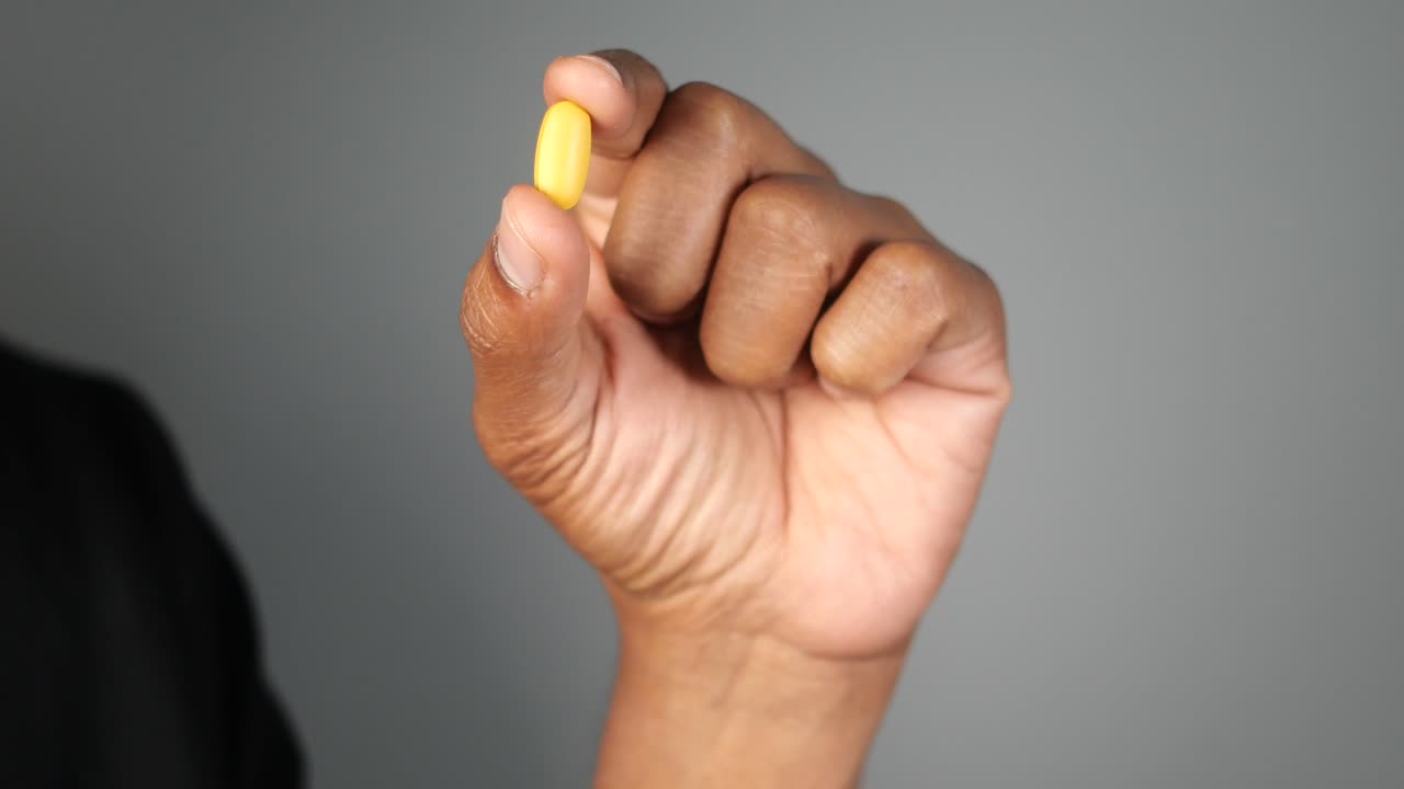 persona que sostiene una píldora amarilla