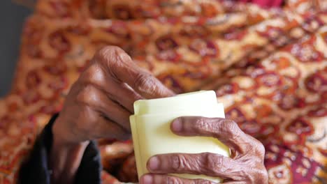 Senior-woman-using-petroleum-jelly-onto-skin-at-home-close-up