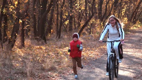 mother and son cycling in autumn forest