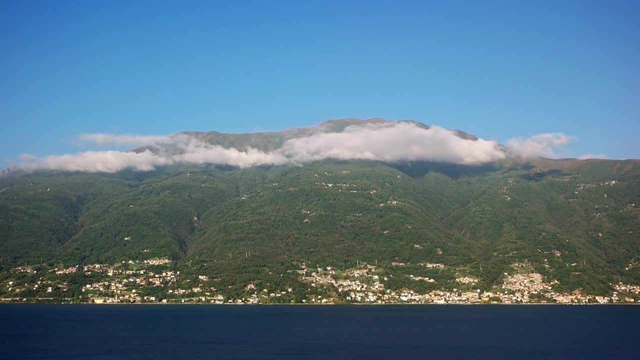 코모 호수 (lake como) 에서 벨레라 (bellera) 마을과 함께 산 위에 낮은 구름의 비디오. 호수의 물은 프레임의 아래쪽에 있고 구름은 언덕의 꼭대기에 그림자를 던집니다.