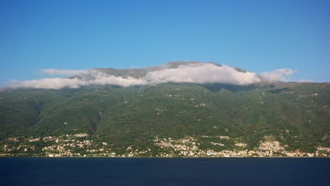 코모 호수 (lake como) 에서 벨레라 (bellera) 마을과 함께 산 위에 낮은 구름의 비디오. 호수의 물은 프레임의 아래쪽에 있고 구름은 언덕의 꼭대기에 그림자를 던집니다.