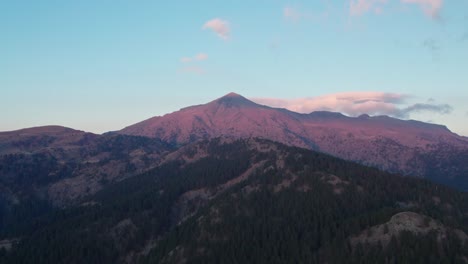 un dron vuela a gran altura revelando el pico de la montaña smolikas en grecia mientras se pone el sol