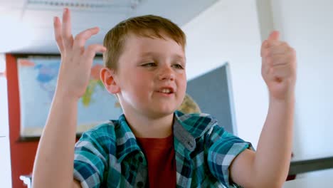 caucasian schoolboy sitting at desk and counting with his finger in a classroom 4k