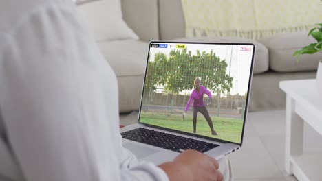 usando las manos portátil con afroamericano jugador de fútbol masculino jugando partido en la pantalla