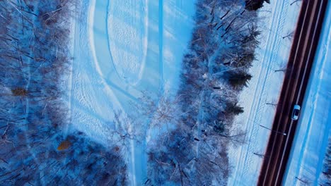 Aerial-winter-twilight-Birds-eye-view-flyover-Edmonton's-Victoria-Park-empty-manmade-700m-ice-skating-race-track-by-roadside-forest-access-to-Canada's-largest-outdoor-municipal-funded-park-arena4-4