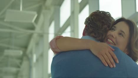Back-View-Of-The-Man-Hugging-His-Pretty-Happy-Wife-Or-Girlfriend-When-They-Meeting-In-The-Airport