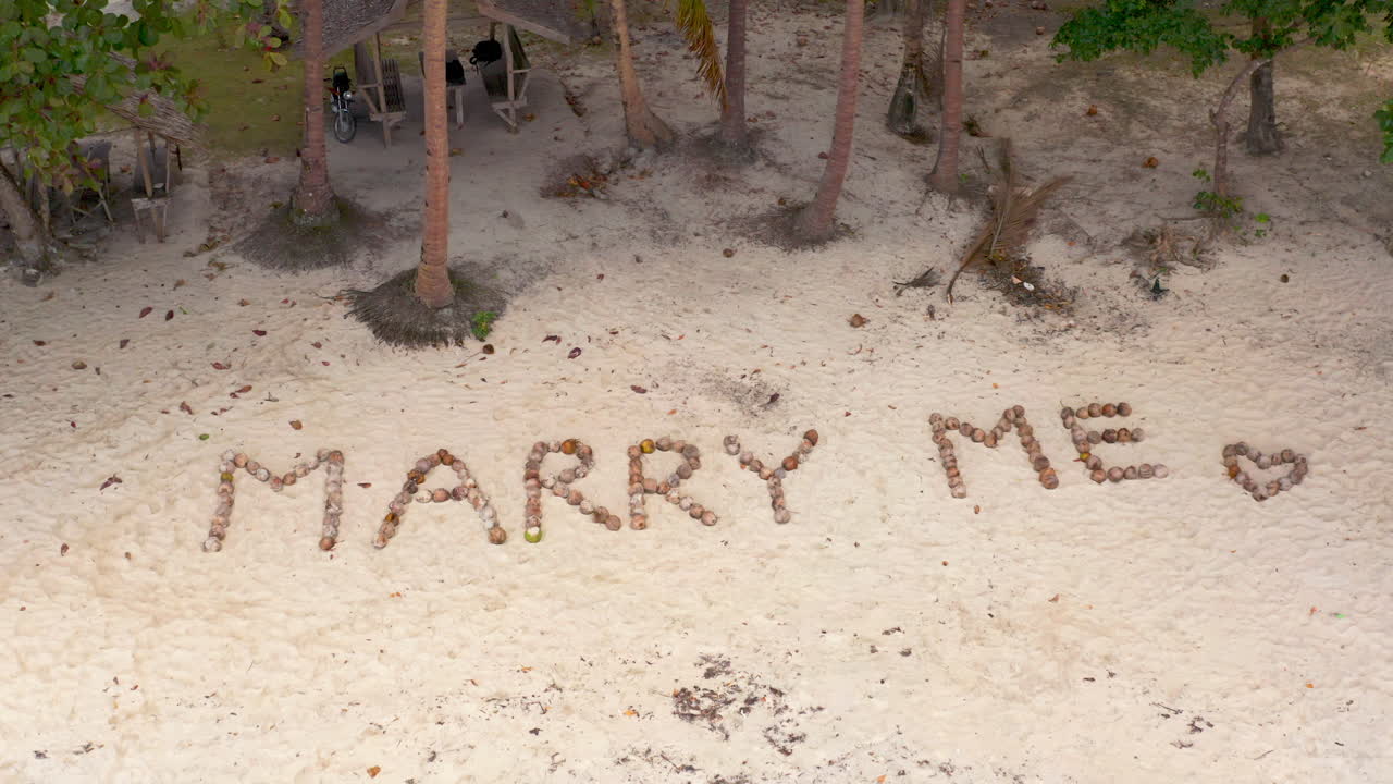 Marry Me message written with coconuts on a tropical beach