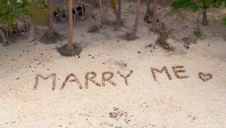marry me message written with coconuts on a tropical beach
