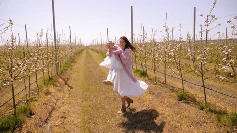 happy mother and daughter are having fun in the green blooming apple orchard.