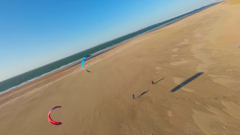 Luftflug-über-Menschen,-Die-Am-Goldenen-Strand-Drachen-Im-Wind-Steigen-Lassen