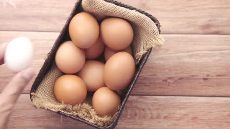 hand picking a white egg from a basket of brown eggs