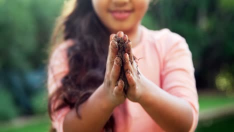 girl rubbing mud on her hands