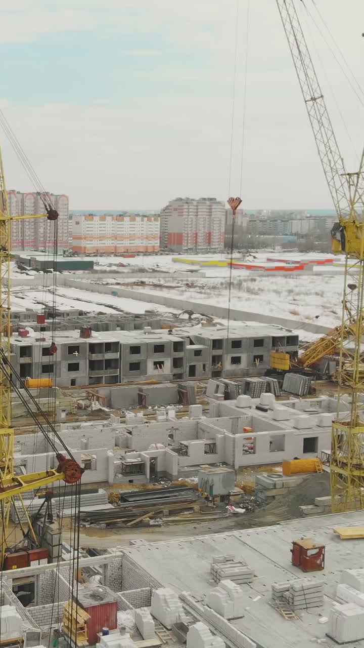 construction site of new house complex surrounded by snowy wasteland against distant residential area aerial view