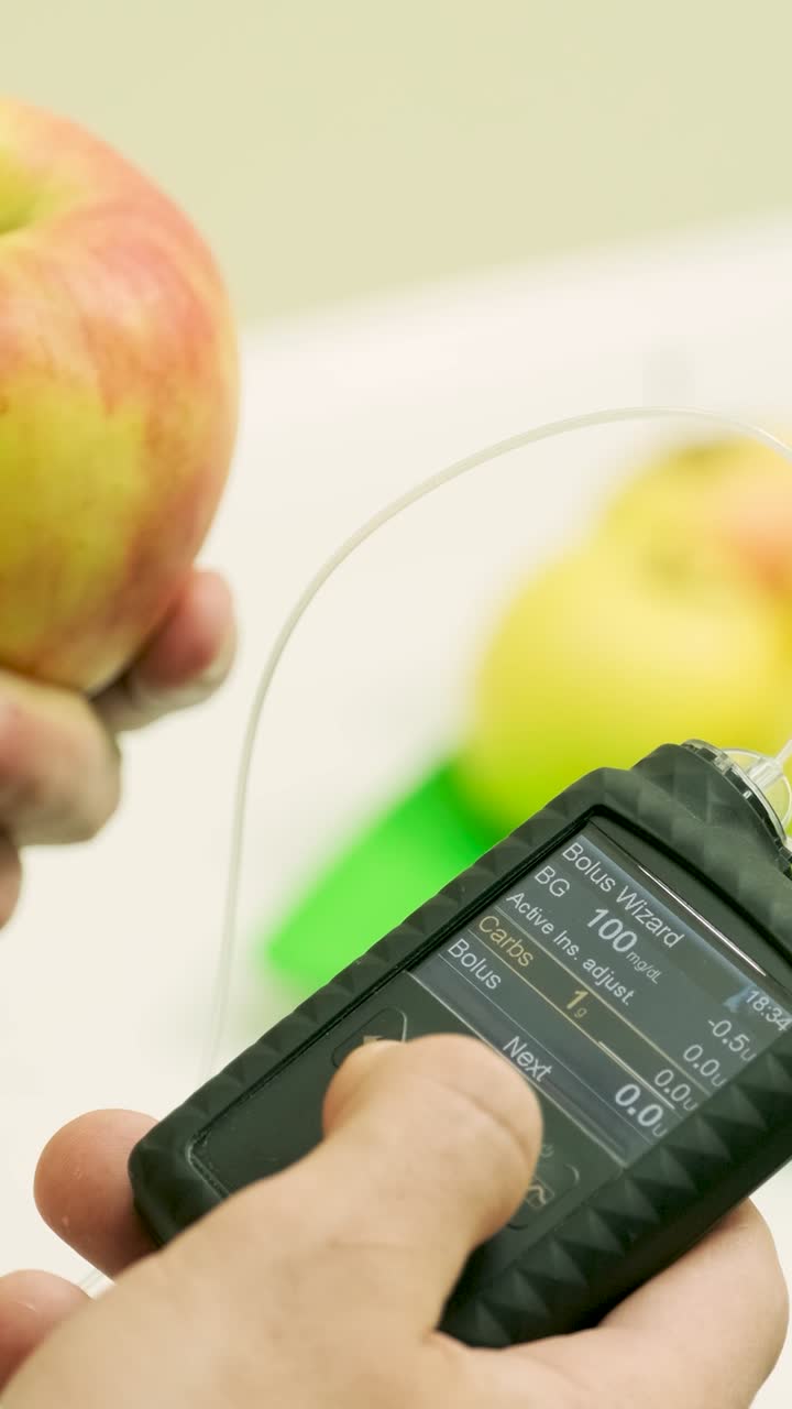 Person Using Insulin Pump to Calculate Carbohydrates for an Apple