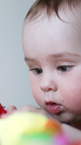 little adorable baby being busy playing with a toy. adorable kid totally focused on his toy. close up. blurred backdrop. vertical video