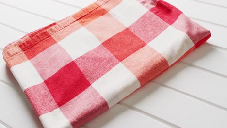 close up of folded red and white checkered blanket on white background with copy space