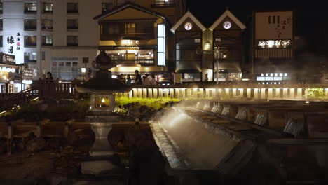 shot of a japanese stone lantern next to the iconic yubatake during evening light up with hot steam rising