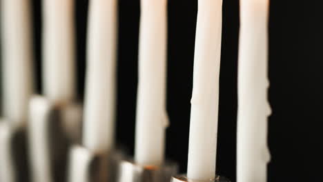disparo de velas blancas encendidas que arden en un candelabro de menorá judía, enfoque selectivo, detalle de primer plano