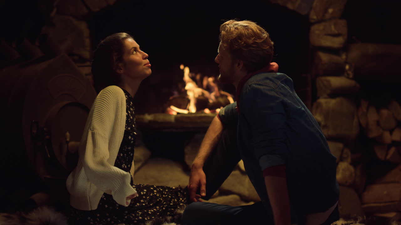 낭만적인 남편 아내는 시골집 벽난로 옆에서 이야기를 나눕니다. 커플은 저녁 데이트를 즐긴다