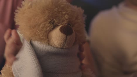 child holding teddy bear with blue scarf