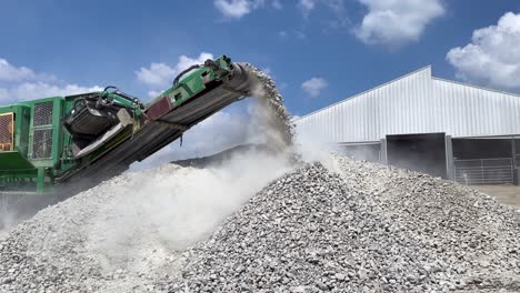 crushed rocks and concrete coming off the belt of a rock crusher creating huge clouds of dust-1