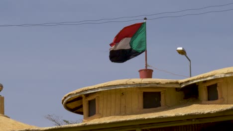 una bandera sudanesa ondeando en el viento en cámara lenta contra un cielo azul