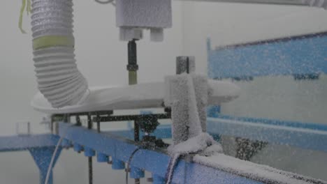 tabla de surf siendo moldeada por una máquina en un taller